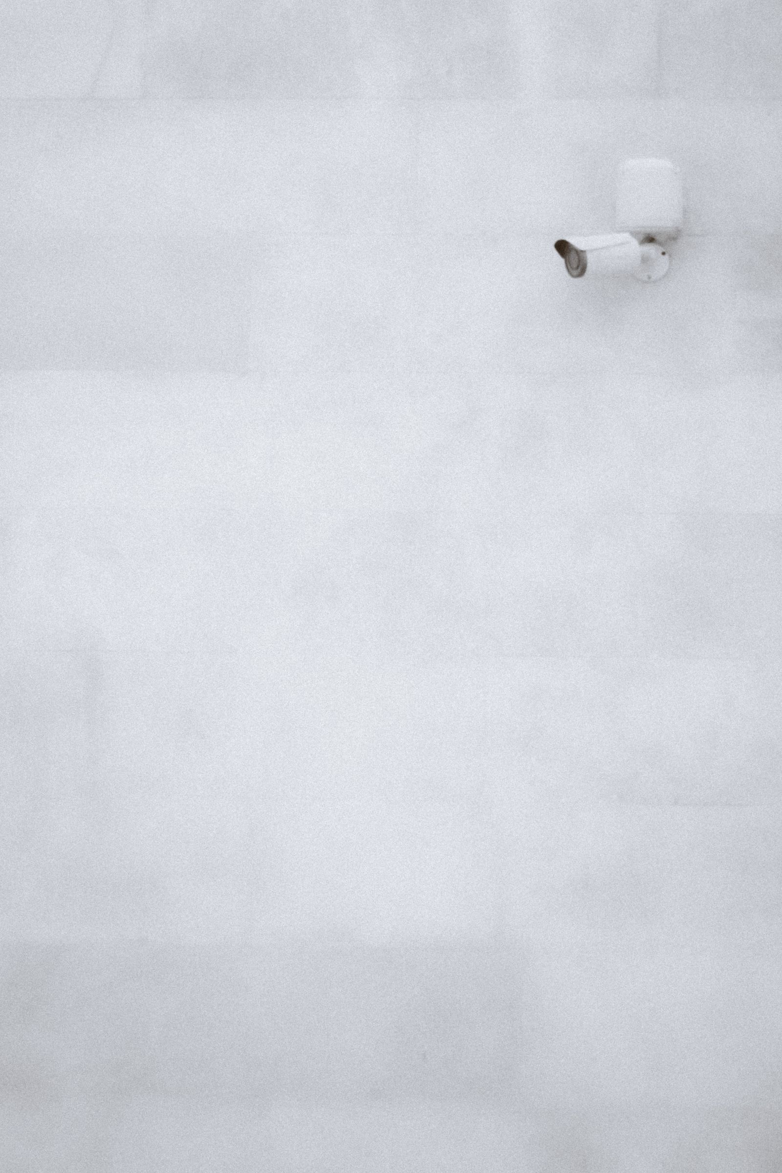 Sample image of a small white security camera high on a pale wall